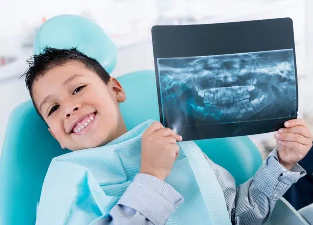 Child holding a dental image showing what is digital X-ray