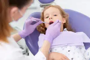 A young child sitting in a purple dental chair during a dental examination
