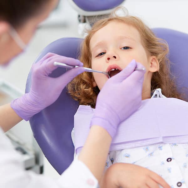 A young child sitting in a purple dental chair during a dental examination