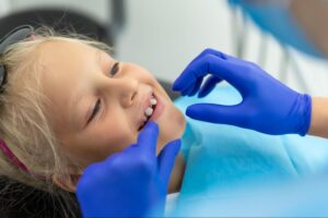 A close-up of a smiling young girl wearing a dental retainer during an orthodontic checkup