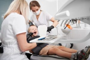 Pediatric dentist in gloves performing treatment on a young boy.