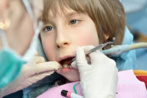 pediatric-dentist-examining-young-boy