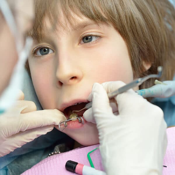 pediatric-dentist-examining-young-boy