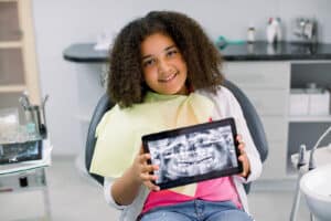 Smiling young girl sitting in a dental chair during a checkup.